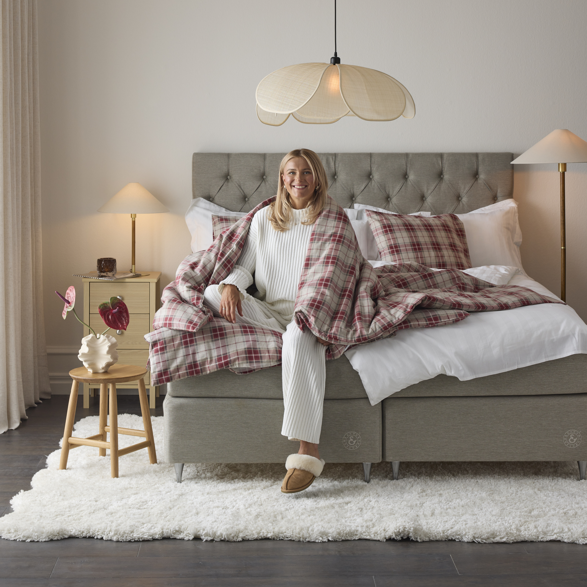 Skidåkaren Frida Karlsson sitter i säng med täcke över axlarna. 