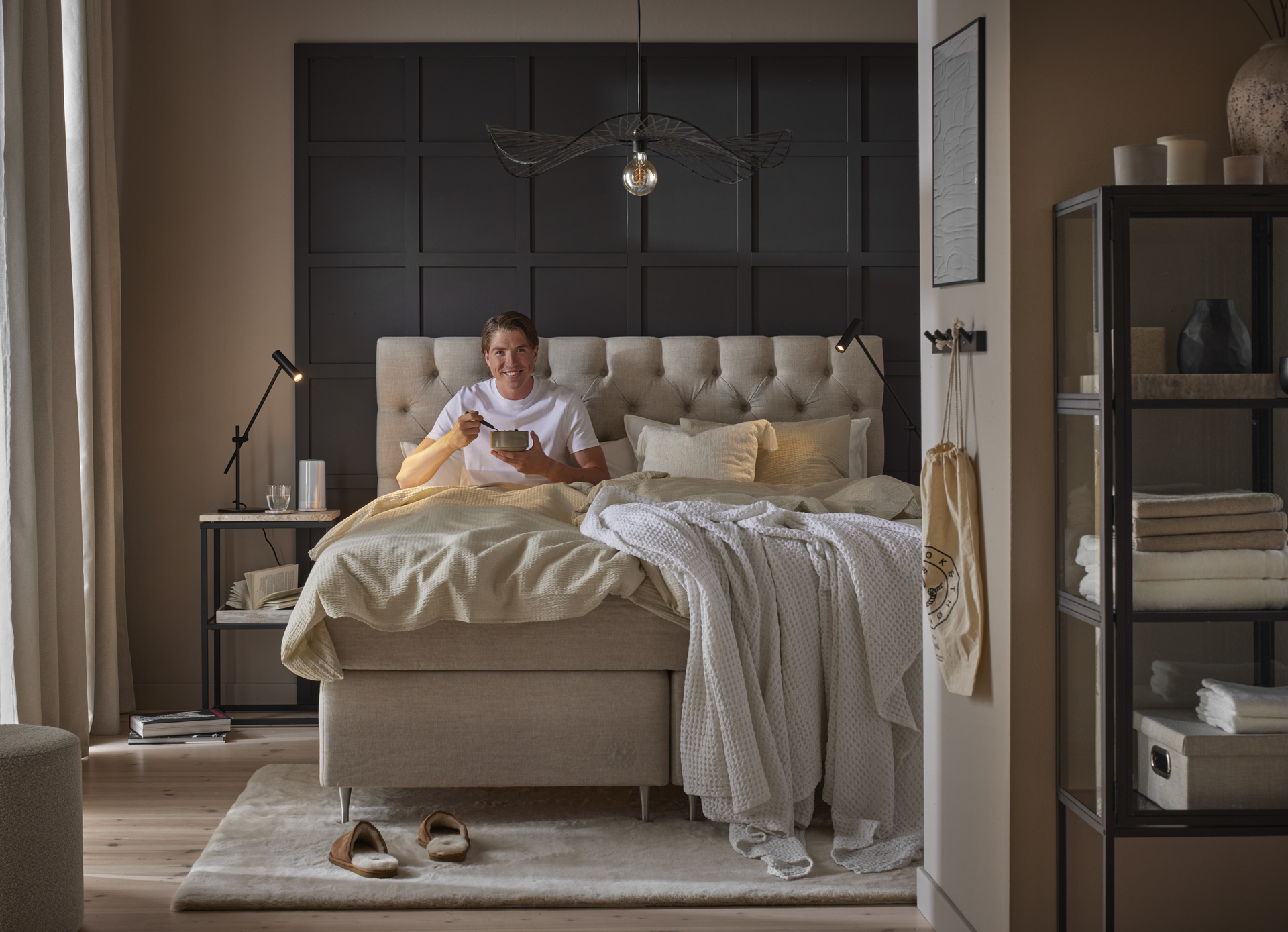 Skidåkaren William Poromaa sitter i en kontinentalsäng från Mio och äter en skål med gröt. 