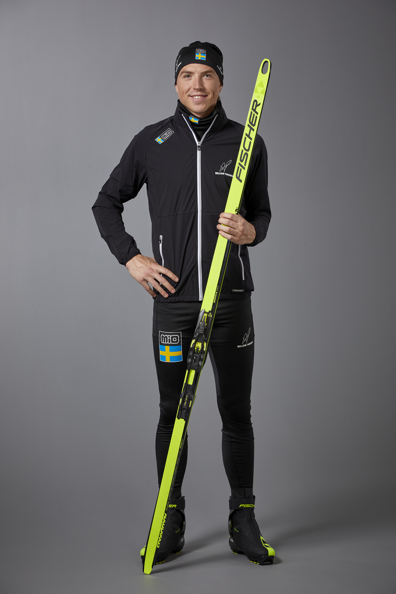 Porträttbild på skidåkaren Frida Karlsson i träningskläder med stavar och skidor.