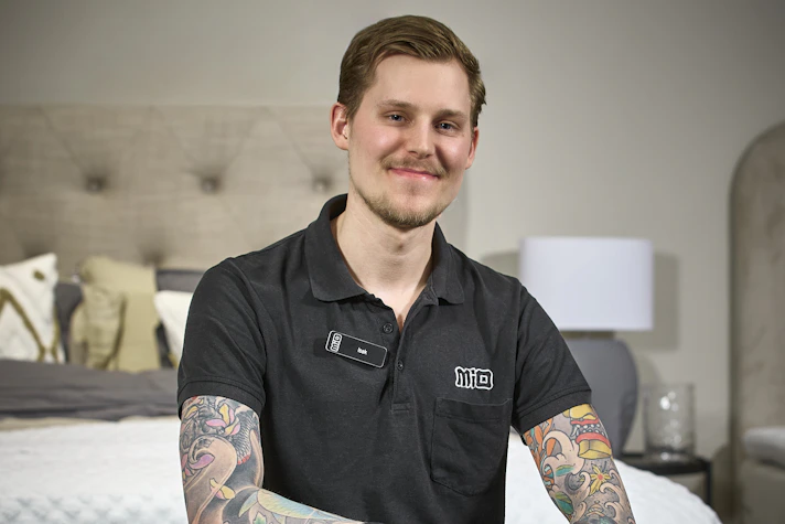 Mios sömnexpert Isak Landström på Mio Skövde sitter ned på sängkant.