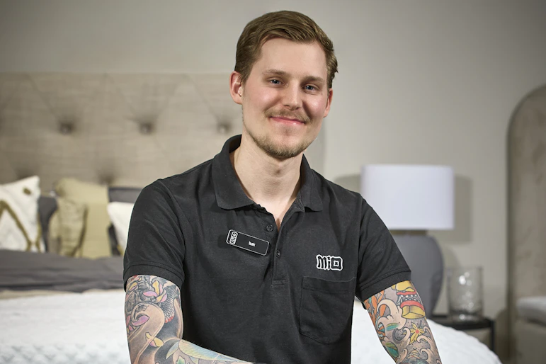 Mios sömnexpert Isak Landström på Mio Skövde sitter ned på sängkant.