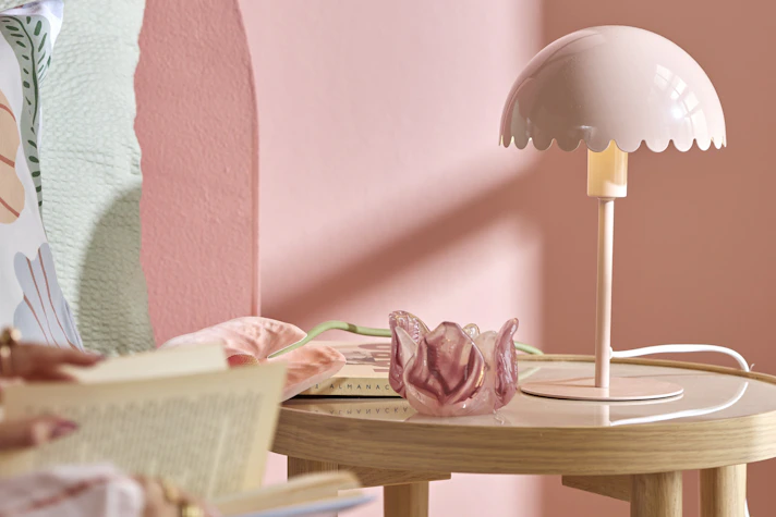 en rosa lampa står i ett rosa sovrum bredvid en säng