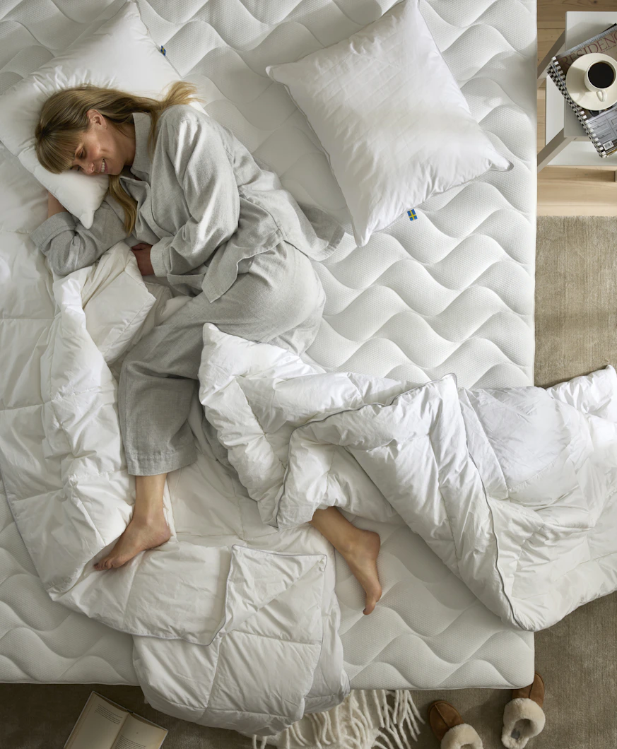 en tjej ligger på en obäddad bäddmadrass med ett täcke och kudde