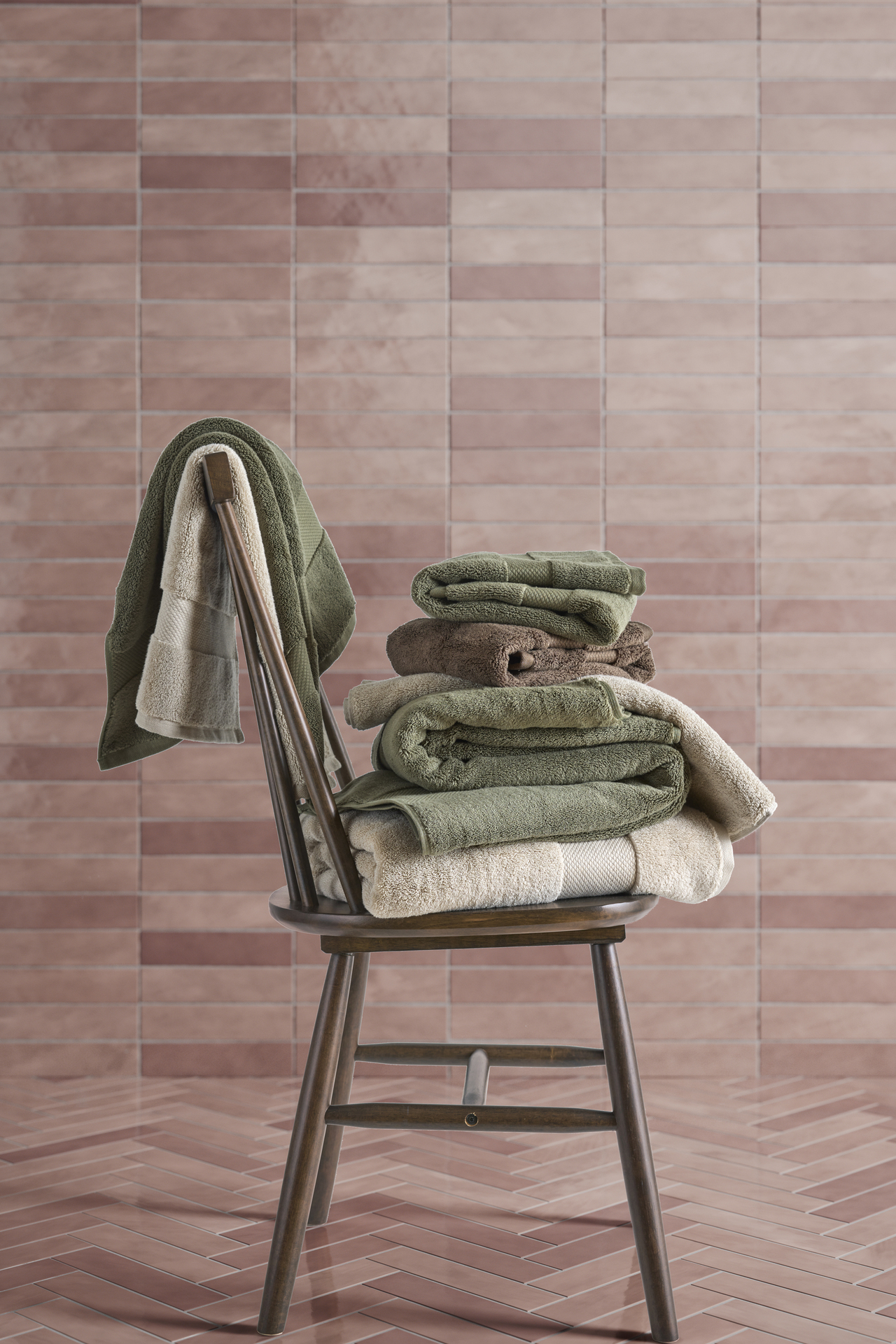 en stol med handdukar i olika färger står framför rosa kakel