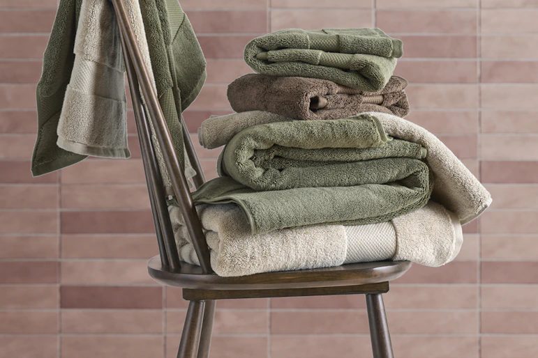 en stol med handdukar i olika färger står framför rosa kakel