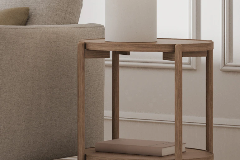 en vit lampa står på ett ljust sidobord i trä bredvid en soffa