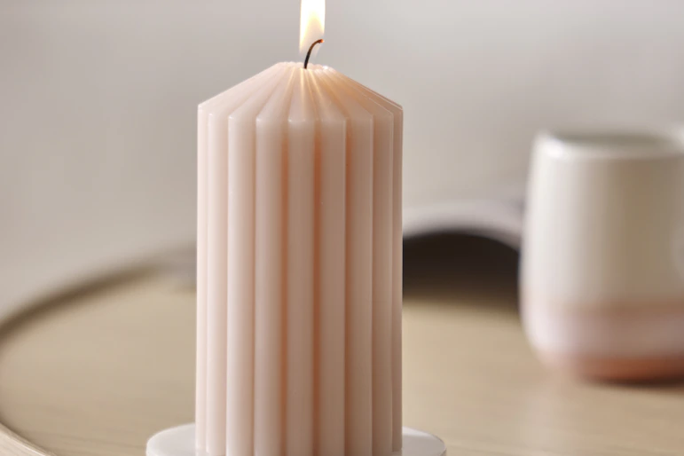 ett rosa räfflat ljus brinner på ett bord