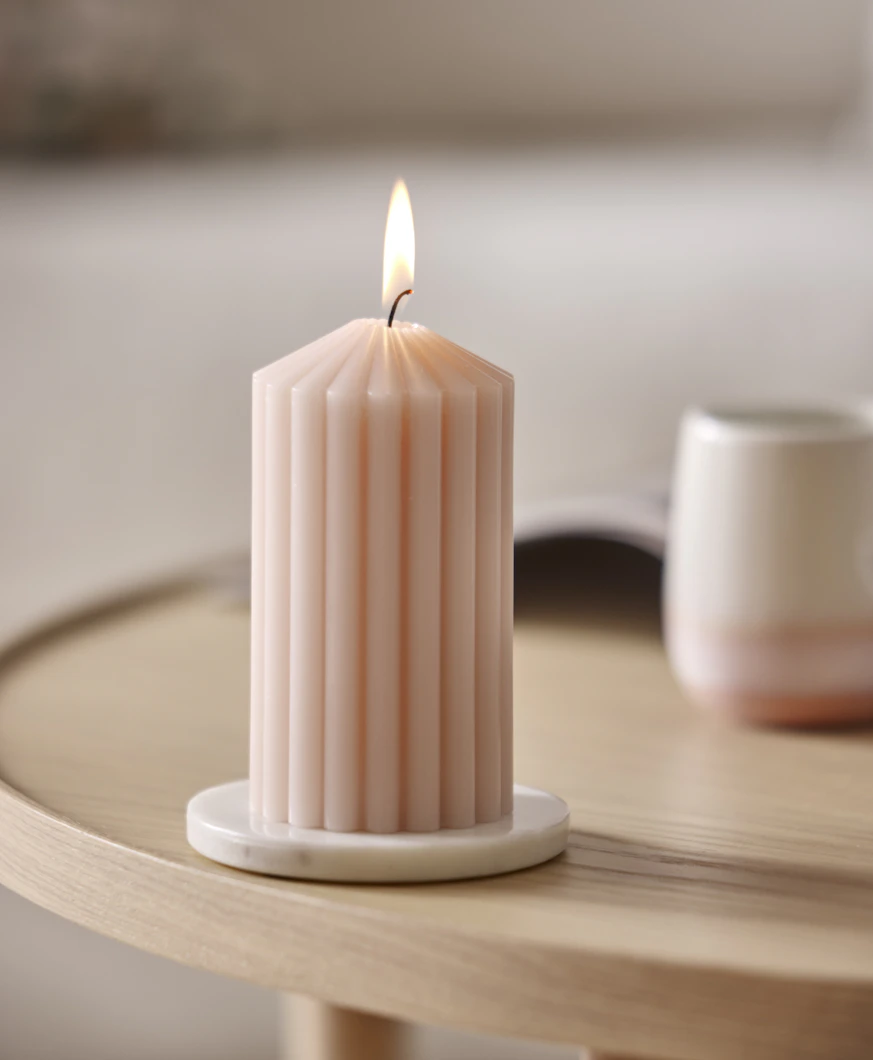 ett rosa räfflat ljus brinner på ett bord