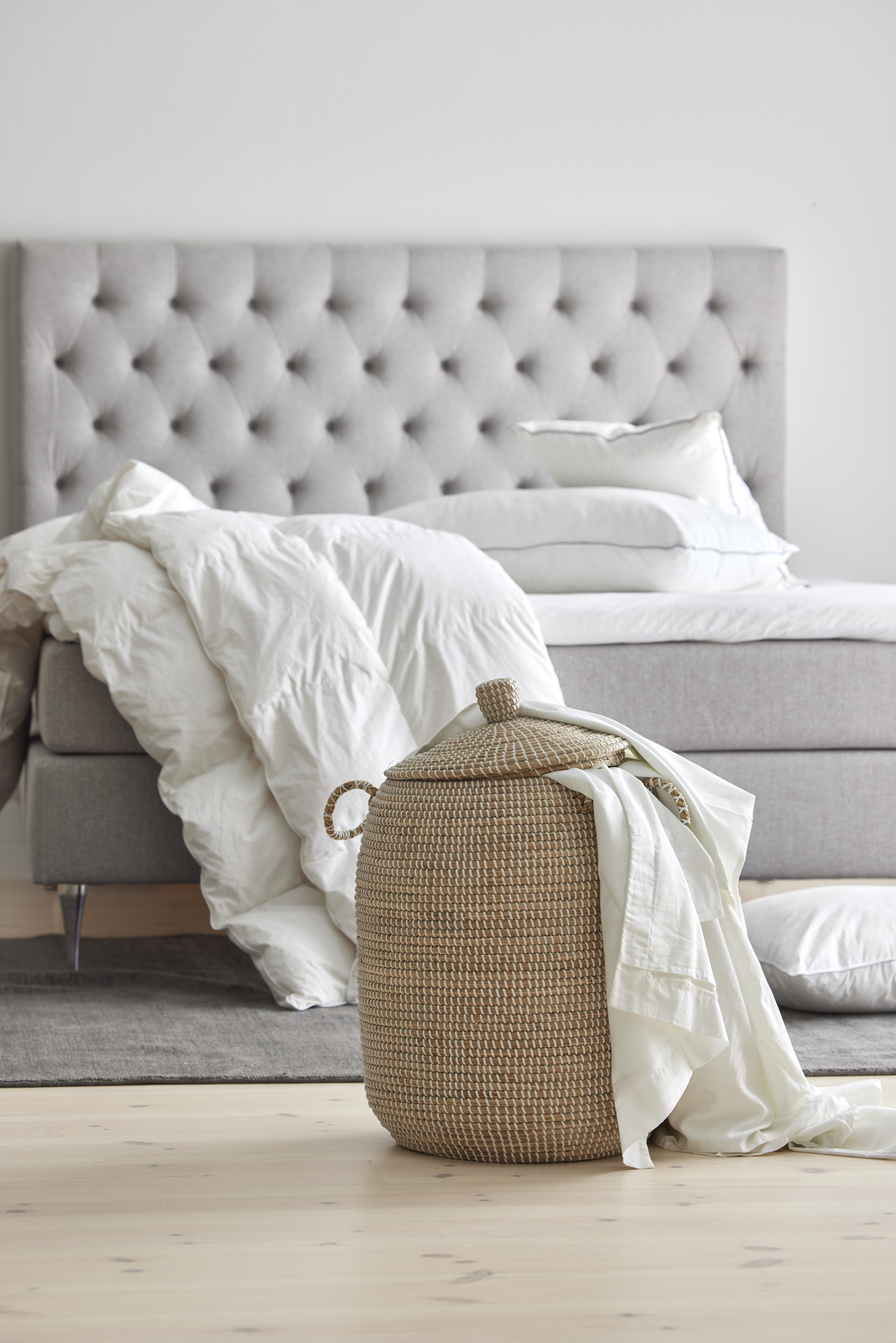 Närbild på flätad korg med madrasskydd som sticker upp ur korgen. 