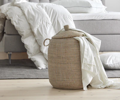 Närbild på flätad korg med madrasskydd som sticker upp ur korgen.