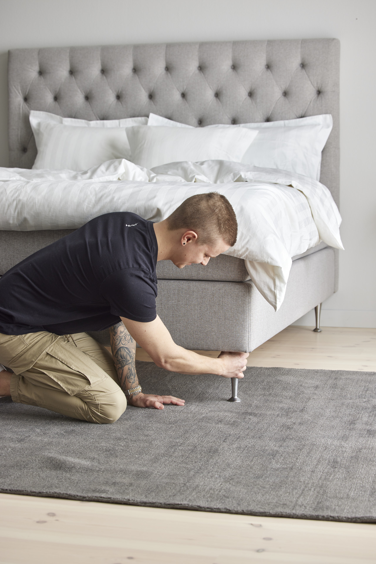 Ung man sitter på knä och drar åt sängben. 