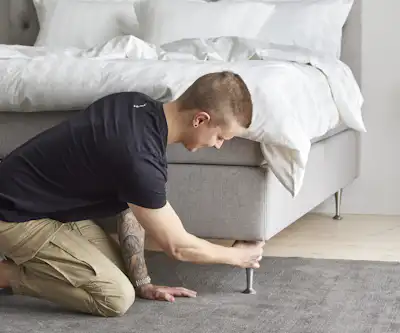 Ung man sitter på knä och drar åt sängben.