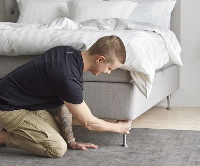 Ung man sitter på knä och drar åt sängben.