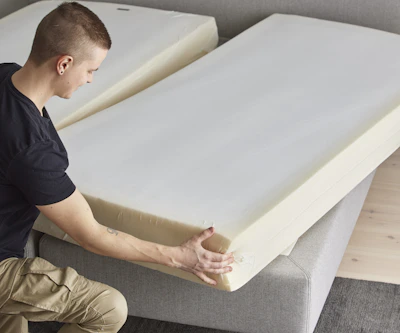 Ung man står på ena knät intill en säng och vrider på sängkassetten.