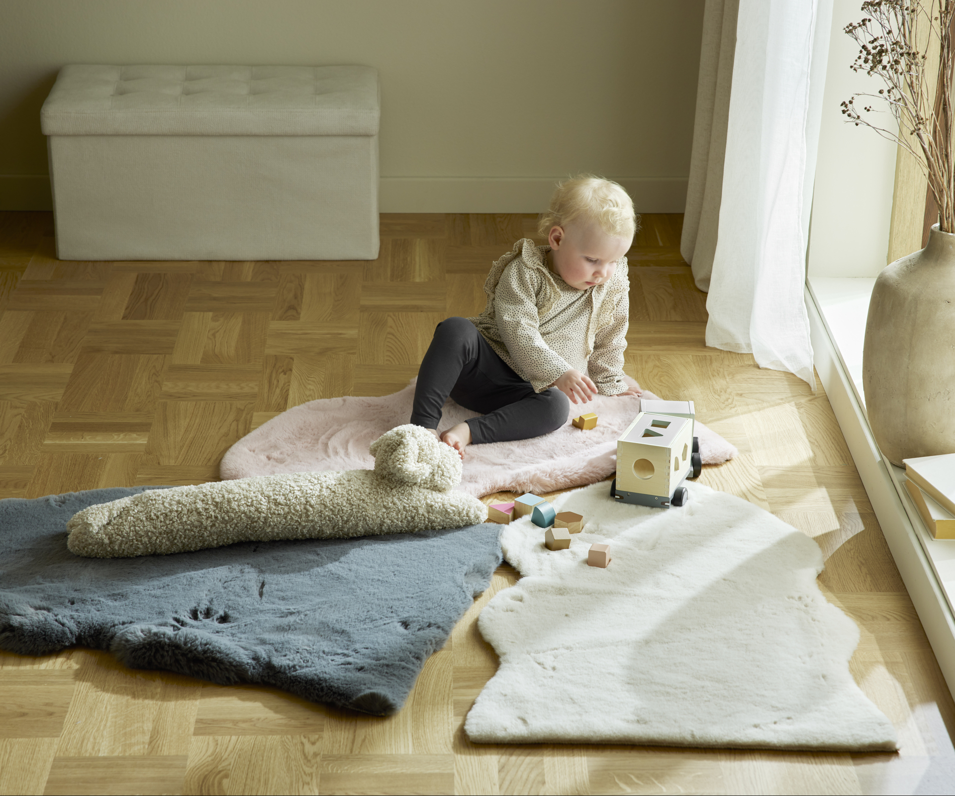 ett litet barn sitter på konstfällar på golvet och leker