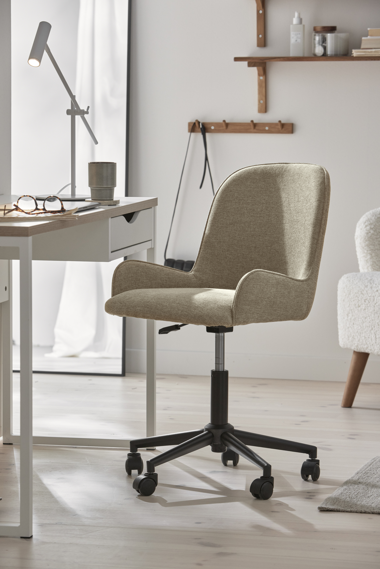 en beige skrivbordsstol står i ett ljust rum framför ett vitt skrivbord