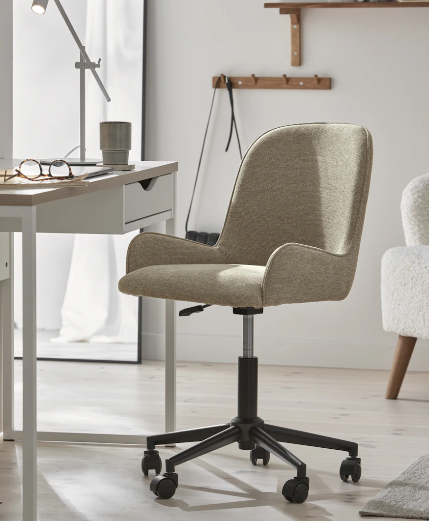 en beige skrivbordsstol står i ett ljust rum framför ett vitt skrivbord
