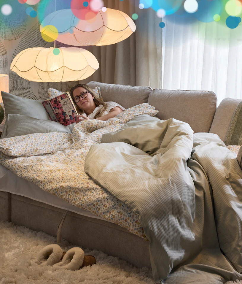 en utbäddad bäddsoffa där en person ligger och läser