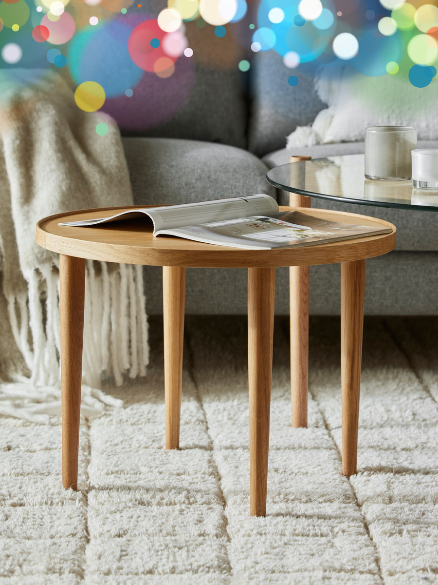 ett runt soffbord i ek står framför en soffa på en vit matta