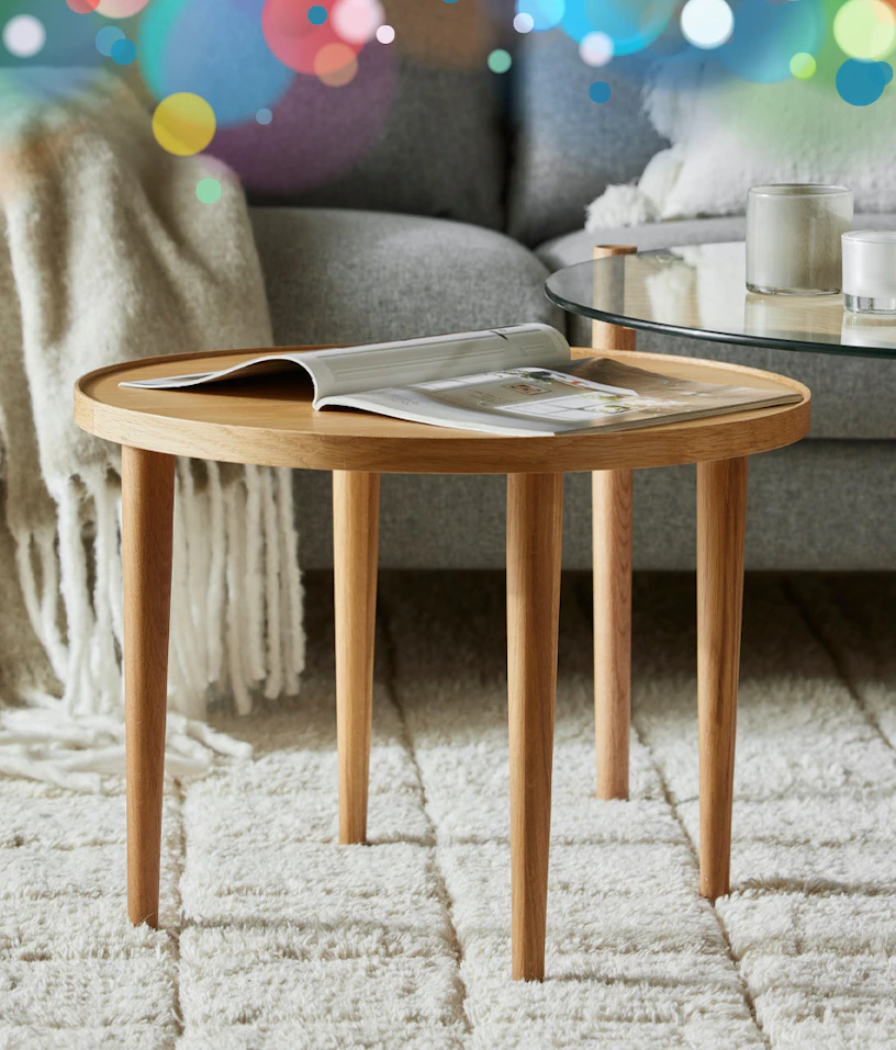ett runt soffbord i ek står framför en soffa på en vit matta