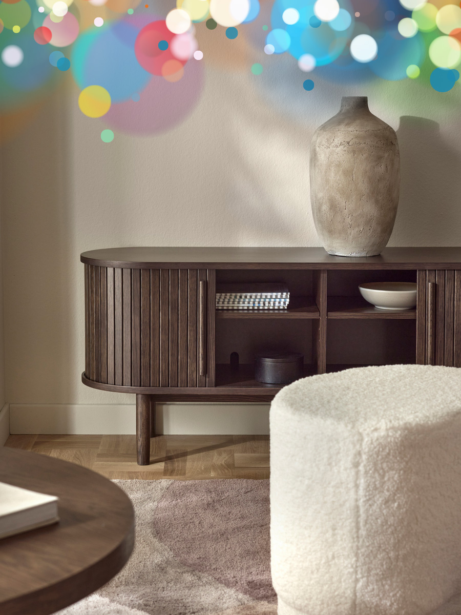 en brun tv-bänk står mot en beige vägg med en urna på