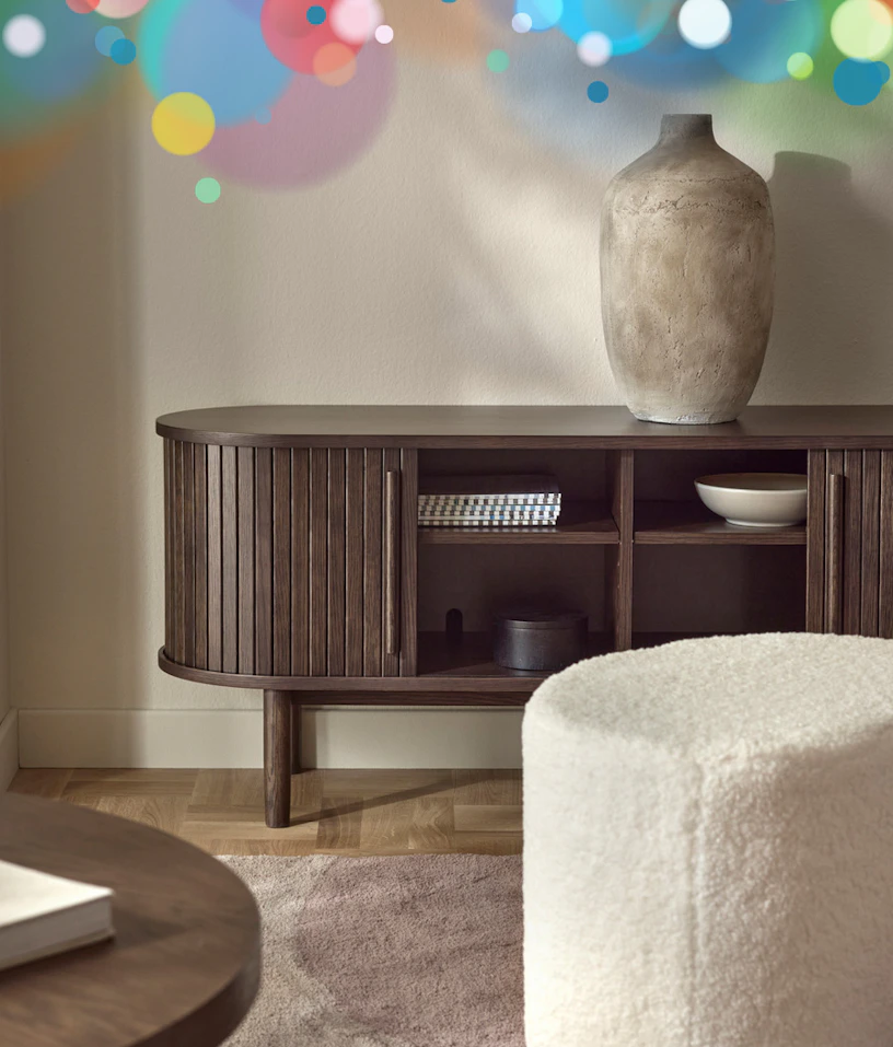 en brun tv-bänk står mot en beige vägg med en urna på