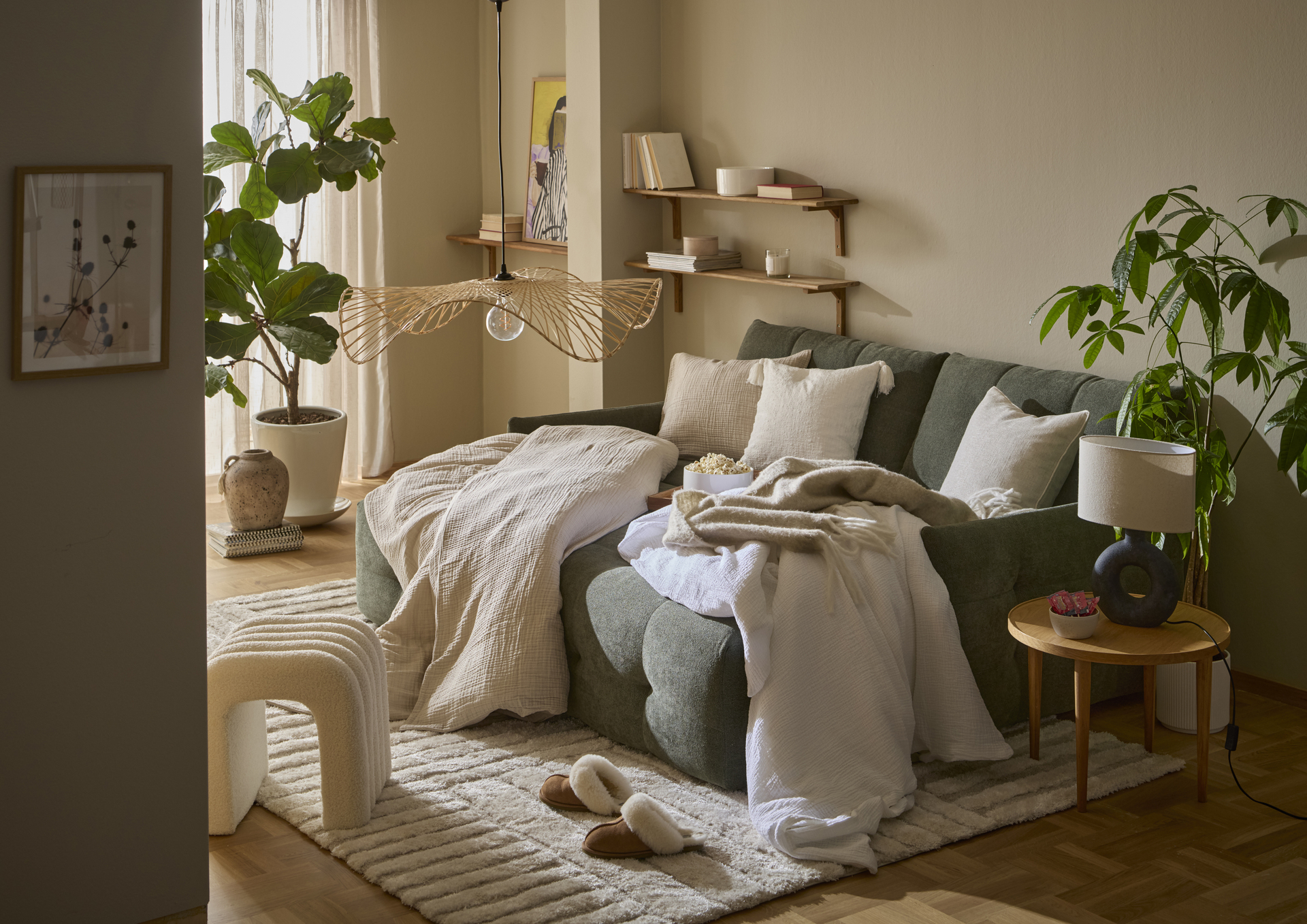 I en grön bäddsoffa ligger fluffiga täcken och kuddar