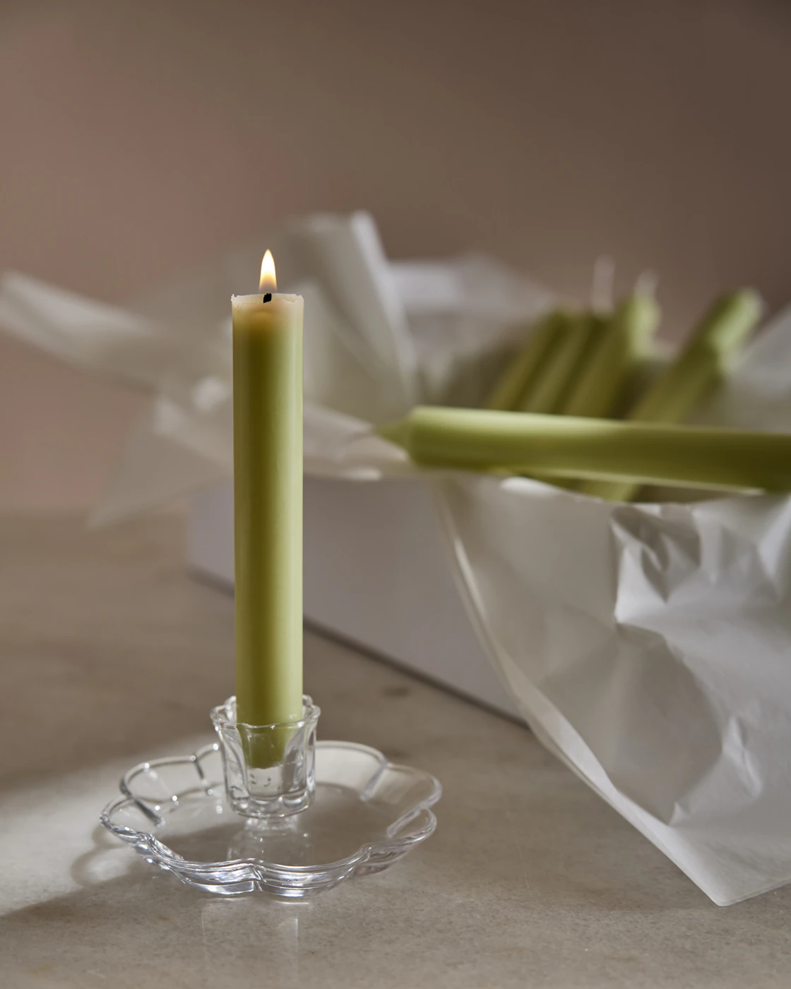 En klar blomformad ljusstake och ett grönt rustikljus.