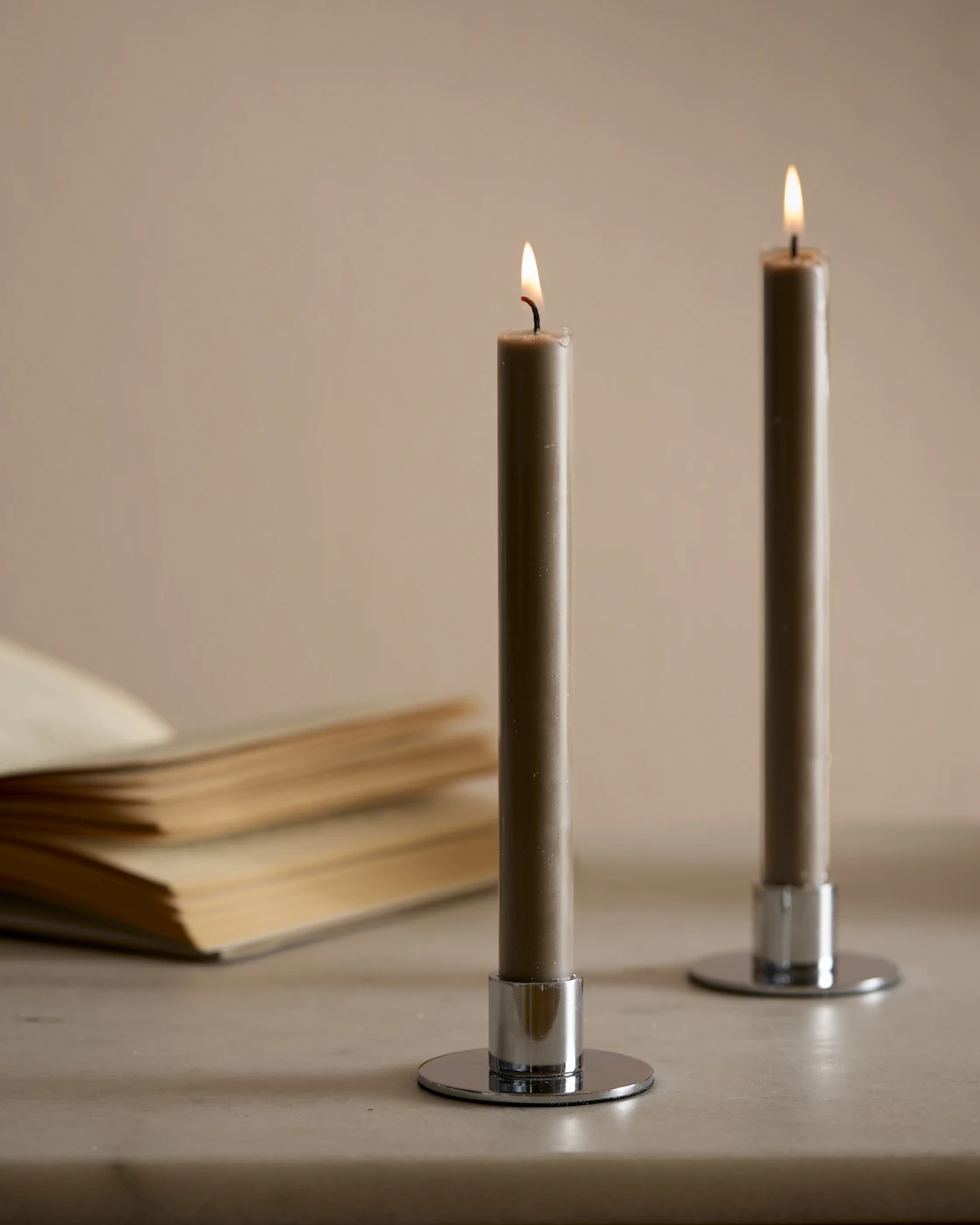 Två silverfärgade ljsstakar med bruna rustikljus.