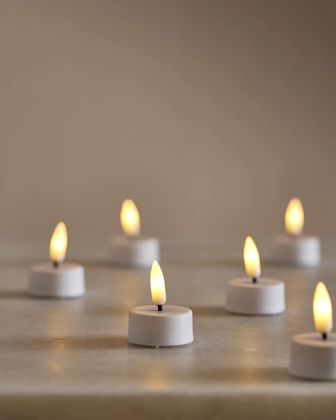 Flera LED-värmeljus står på ett bord.