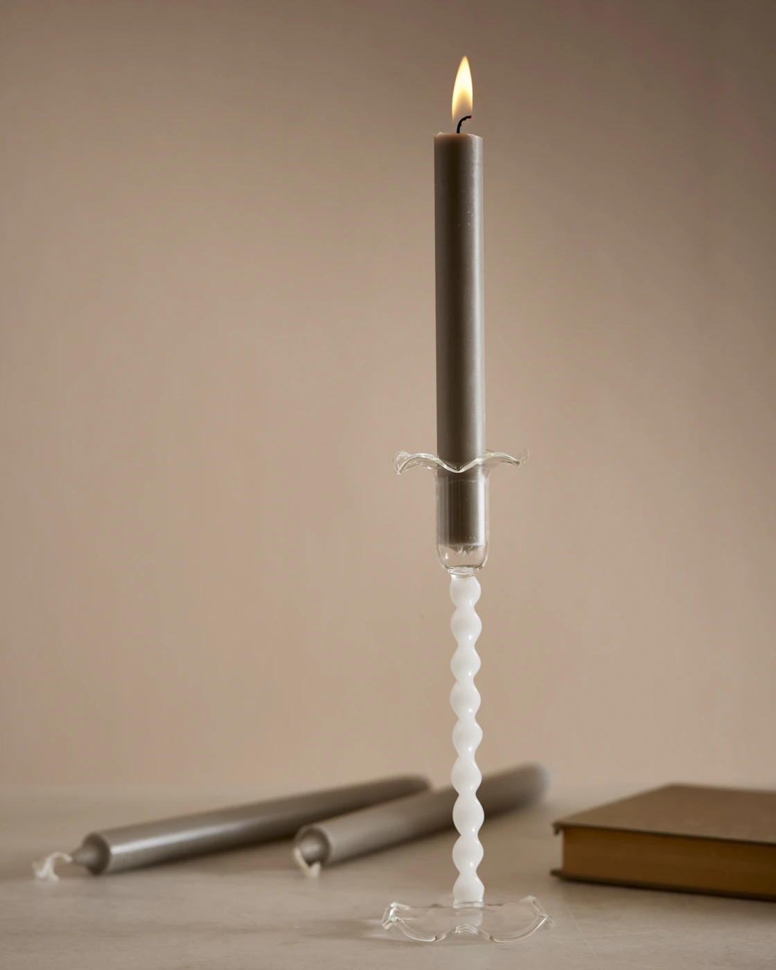 En swirlad vit ljusstake och ett grått rustikljus.