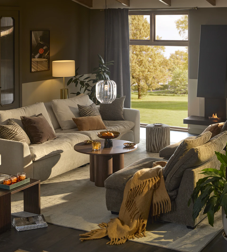 Ett vardagsrum där det står en stor beige soffa mittemot två mörkare fåtöljer.