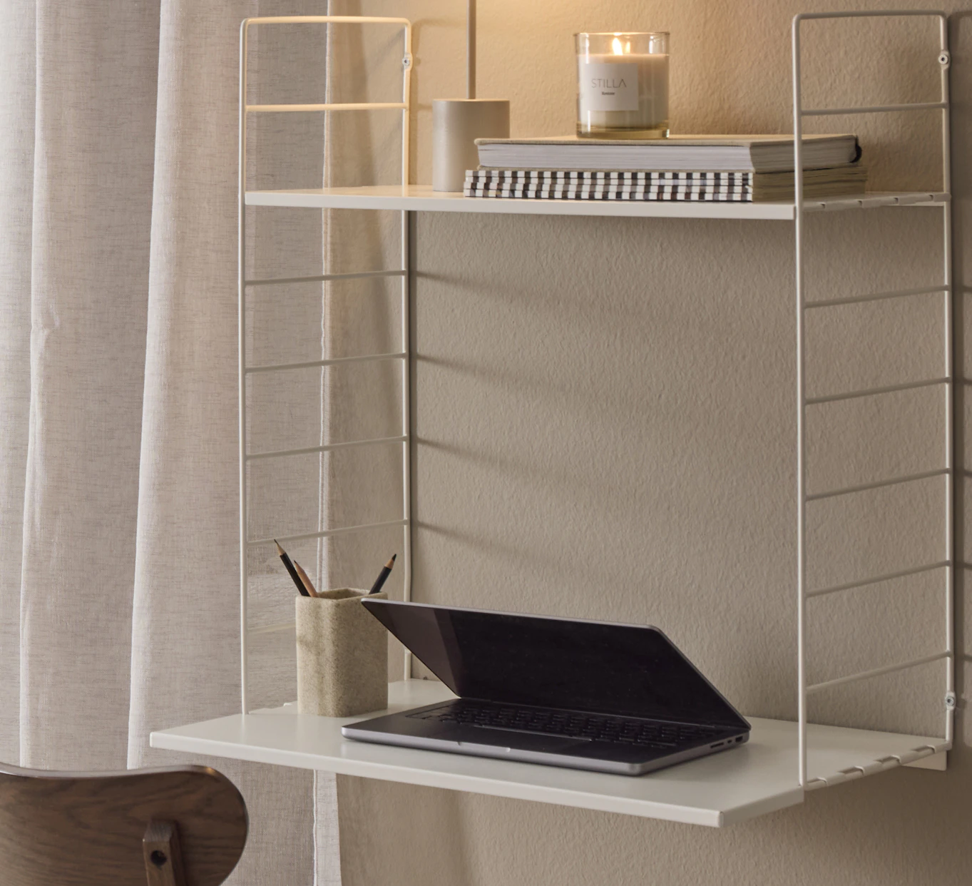 Ett byggbart hyllsystem i vitt fungerar som ett skrivbord