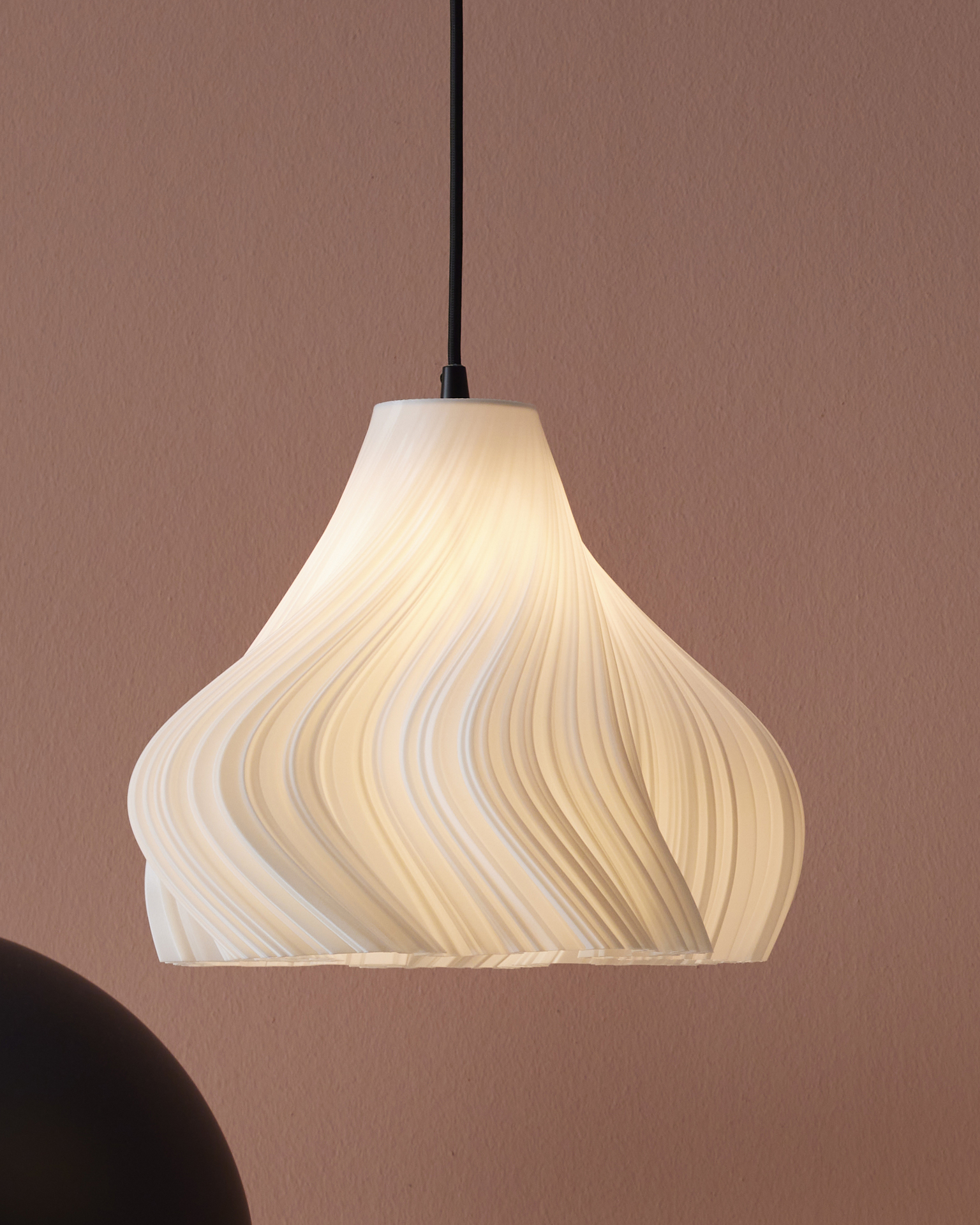 en vit taklampa hänger ned framför en rosa vägg