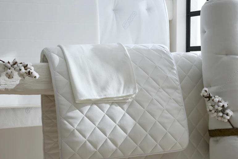 I ett vitt rum hänger bäddmadrasser och madrasskydd på en bjälke