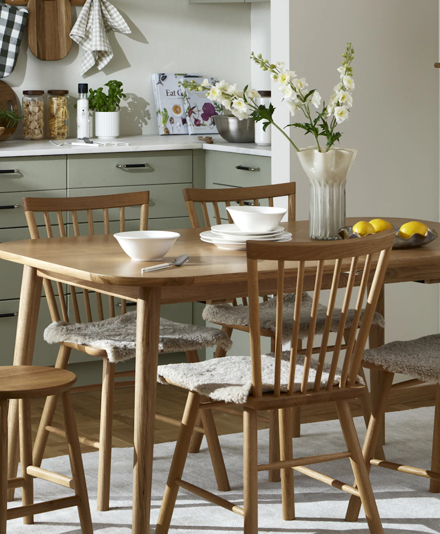 I ett kök i beiga toner står en matgrupp för fyra i ljust trä