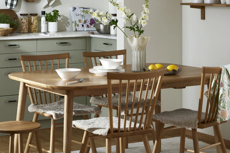 I ett kök i beiga toner står en matgrupp för fyra i ljust trä