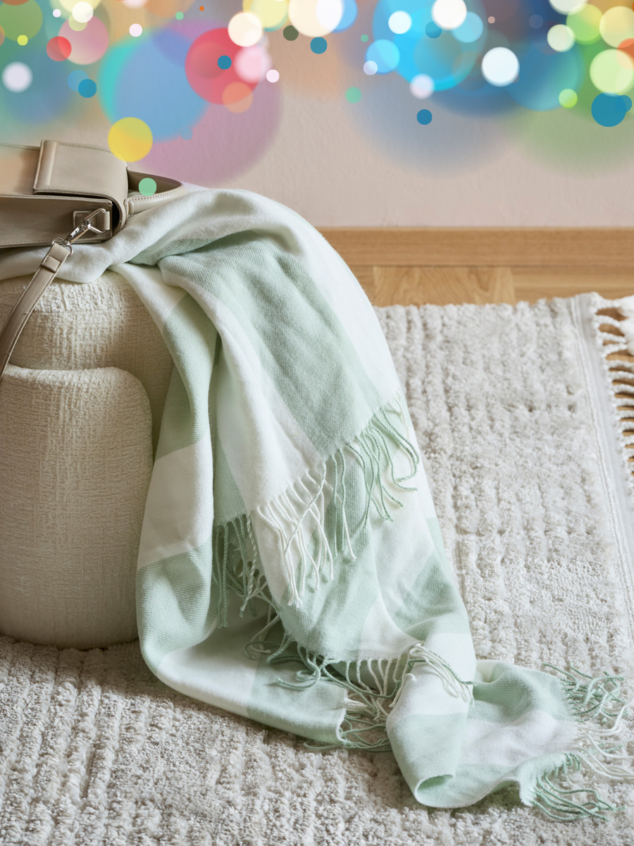 en grön pläd hänger nedför en pall på en beige matta