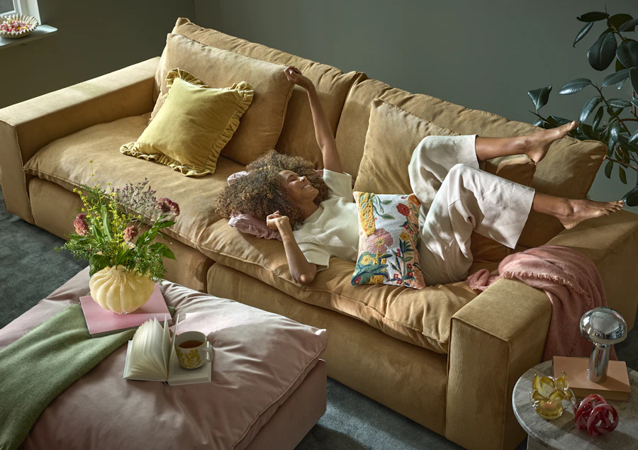 en tjej ligger i en stor gul soffa 