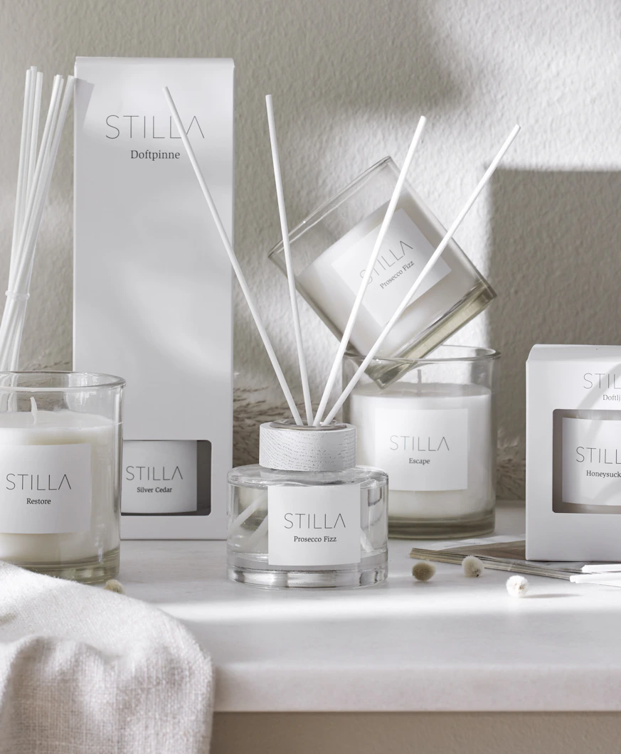 Doftpinnar och doftljus står uppställda på en bänk