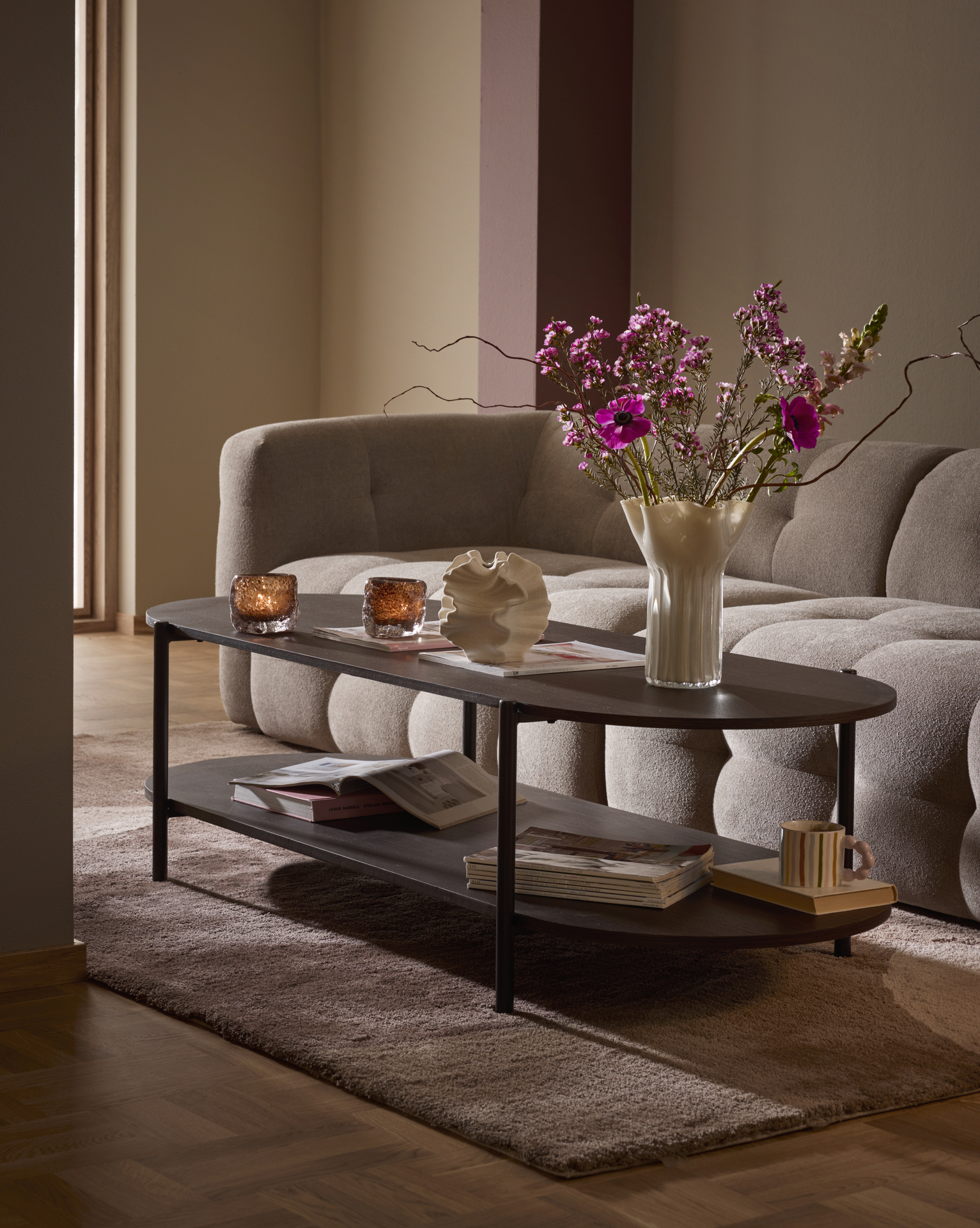 Framför en beige soffa i modern design står ett stort, rektangulärt soffbord i mörkt trä