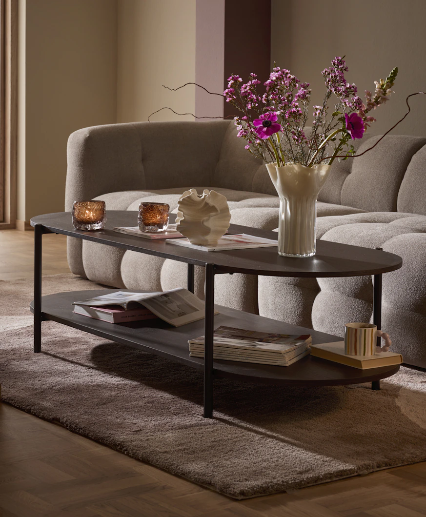 Framför en beige soffa i modern design står ett stort, rektangulärt soffbord i mörkt trä