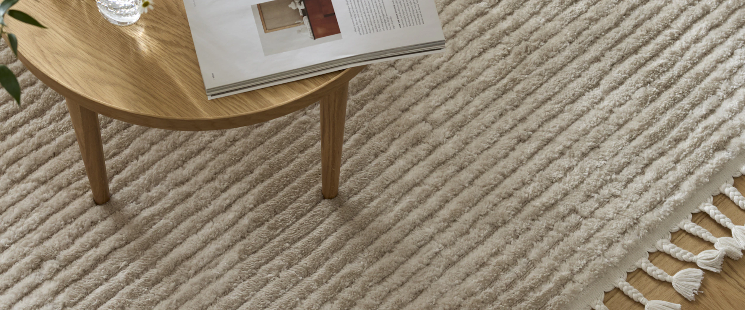 Beige matta med fransad kant i vardagsrumsmiljö.
