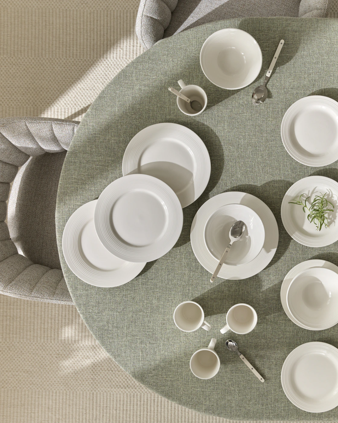 Ovanifrån ses ett matbord med grön duk och servissetet Bianca i 16 delar.