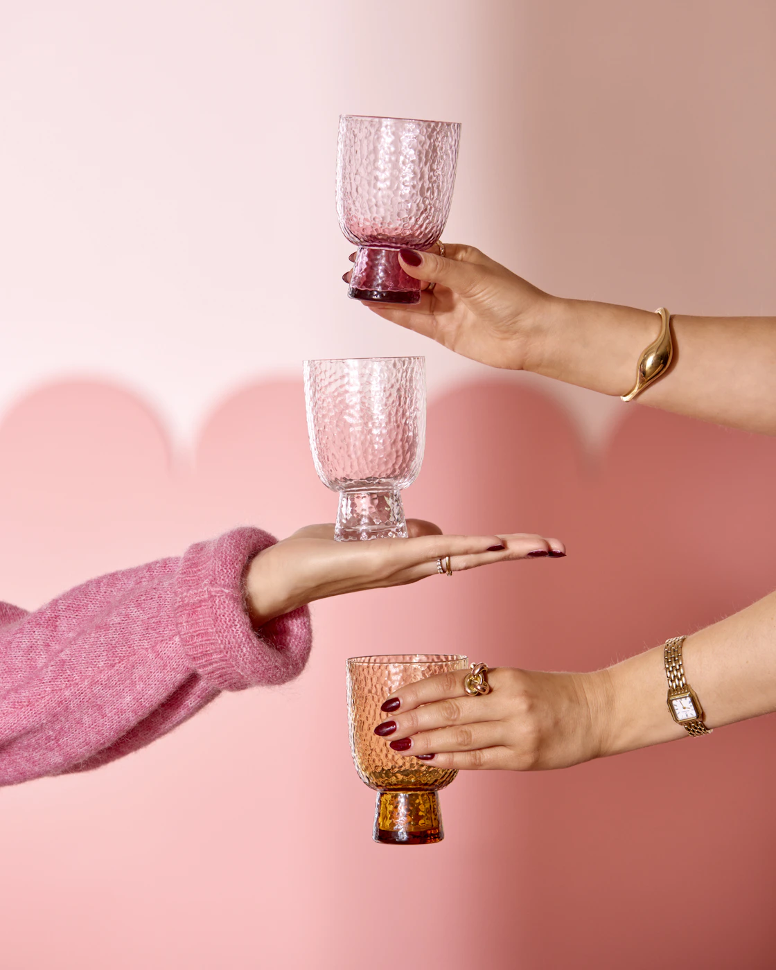 Händer som håller i dricksglas i kulörta färger.