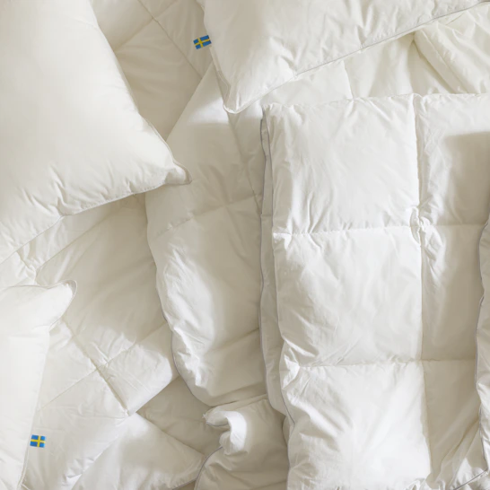 Täcken och kuddar ligger i en obäddad säng.