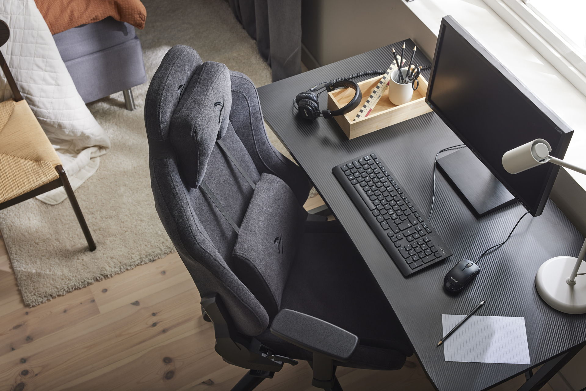 ett svart skrivbord med en dator och en skrivbordsstol intill