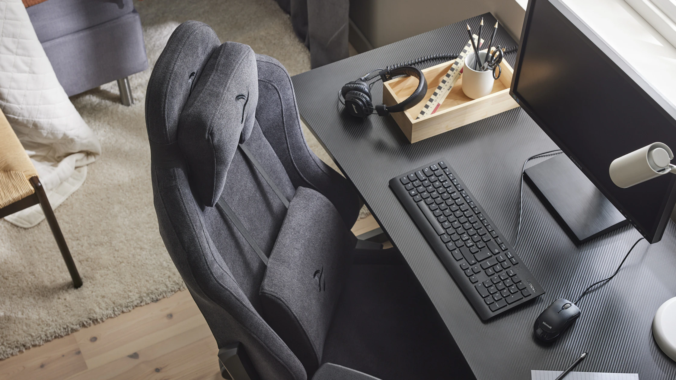 ett svart skrivbord med en dator och en skrivbordsstol intill