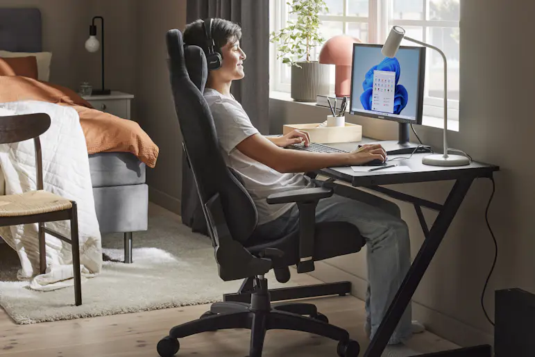 en kille sitter och spelar vid ett skrivbord