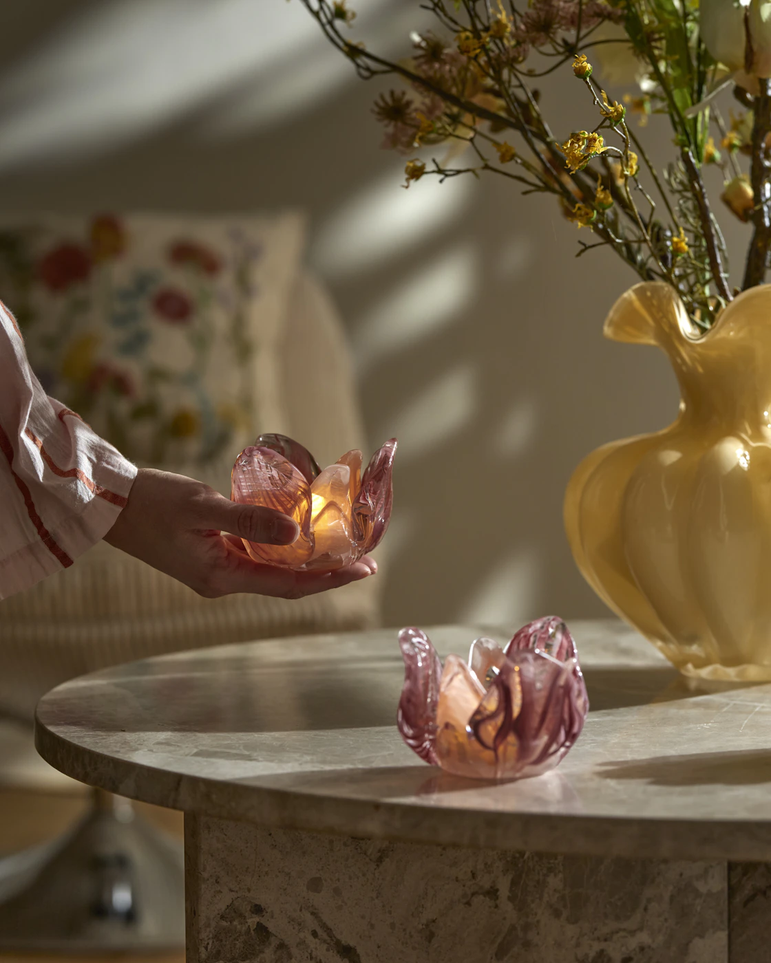 En person håller i en rosa ljusstake i form av en blomma.